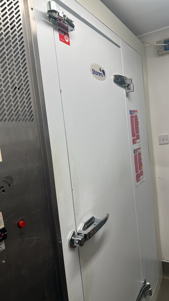 Storers walk-in door with red LIGHT button on the stainless panel